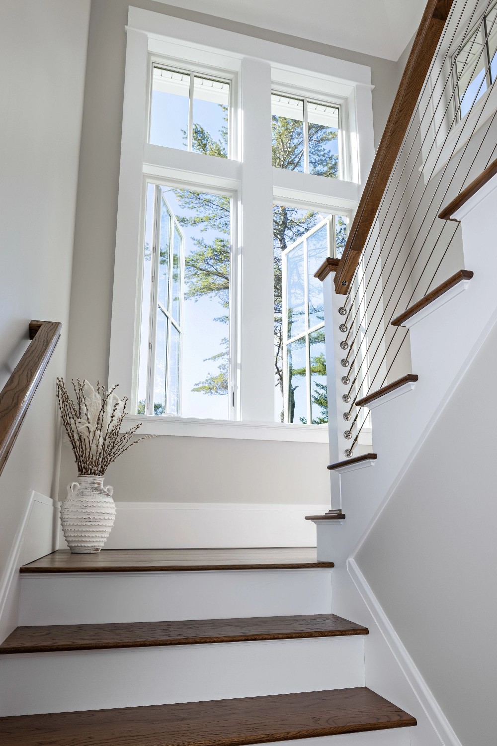 A light and bright stairwell featuring white casement windows open to let in the maximum ventilation.