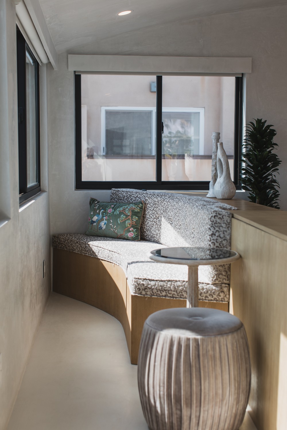 A gliding window in a cozy reading nook with a couch and some chairs.