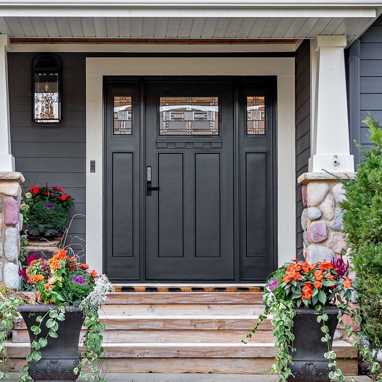 An Ensemble entry door with dual sidelights. The door is black single panel. The sidelights are one third light. There are flower pots in front.